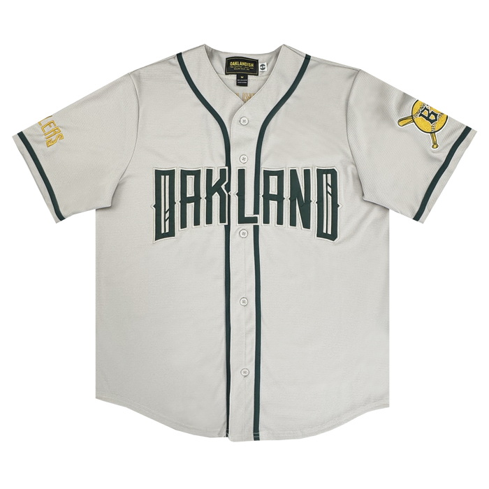 The Oakland Ballers Button Up Jersey by Oakland Ballers features green piping, "OAKLAND" in bold green letters, “A’s” on the left sleeve, and a yellow patch with a green bat and cap—perfect for any fan.