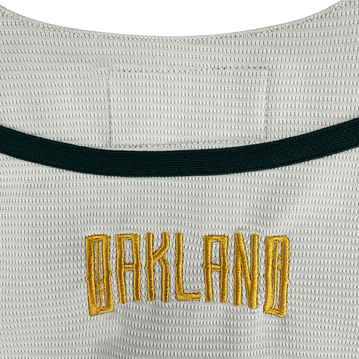 A close-up of the Oakland Ballers Button Up Jersey by Oakland Ballers shows "OAKLAND" in gold block letters with a black border, below a dark green stripe, representing the Pioneer League’s professional baseball team.