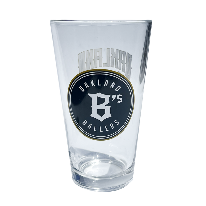 Angled image of pint glass with Oakland Ballers baseball logo in green and gold.