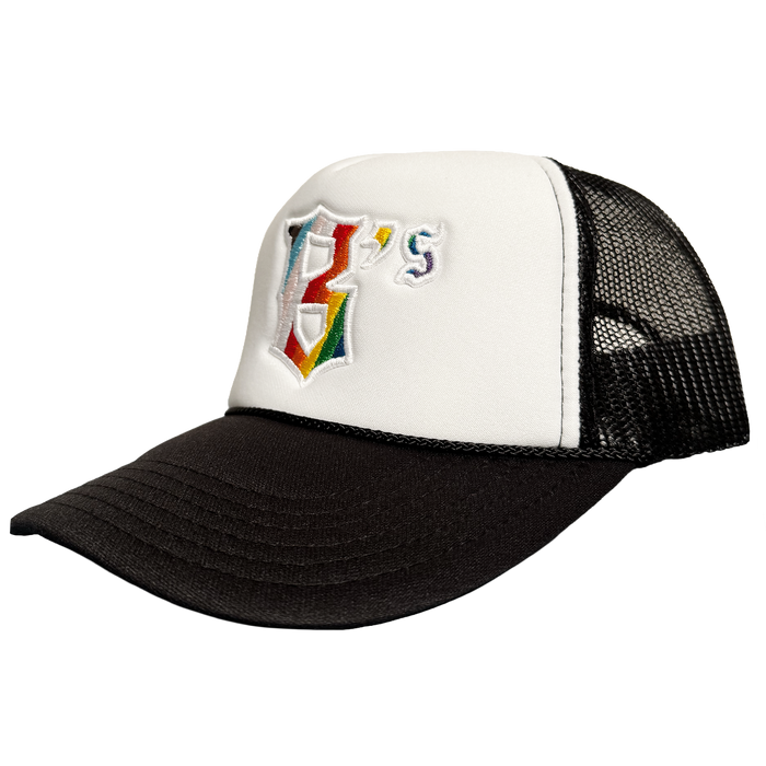 The Oakland Ballers Pride Trucker is a black and white mesh-back hat with a white front panel featuring a rainbow-embroidered "B" and small blue/yellow "'s," representing the Oakland Ballers baseball team.