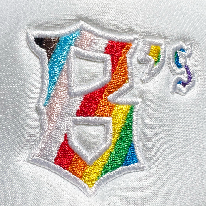 The Oakland Ballers Pride Trucker features a white fabric patch with a rainbow "B's" and stripes in brown, black, blue, white, and pink—a nod to the Progress Pride flag. Brand: Oakland Ballers.