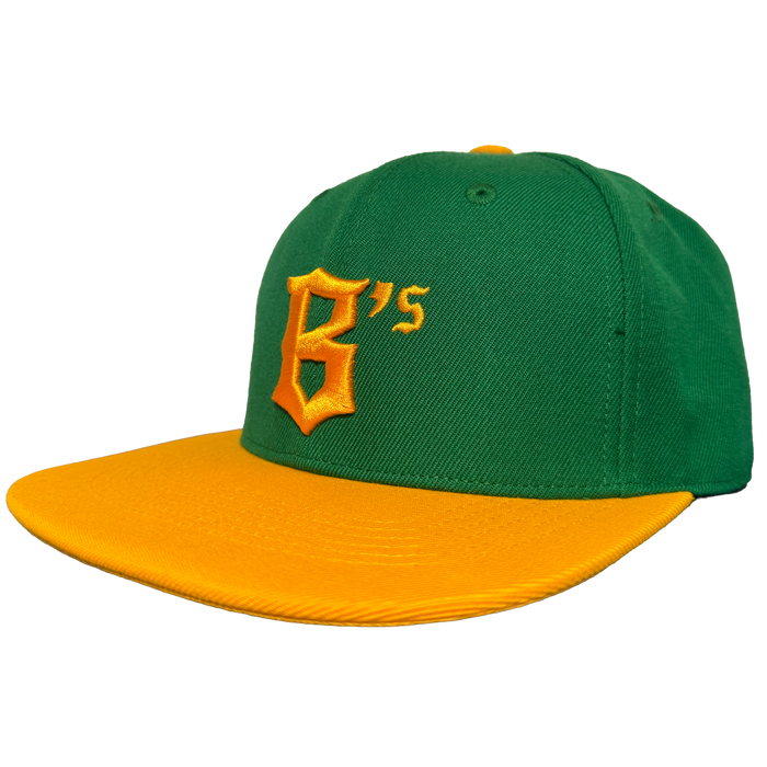 The Oakland Ballers Snapback features a green cap with a yellow brim and button, plus a large yellow embroidered "B" and smaller "'s" on the front—boldly celebrating the Oakland Ballers’ team colors. Plain white background enhances its vibrant look.