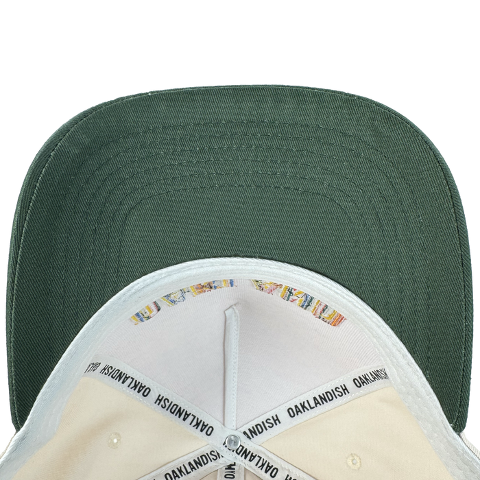 A top-down view of the Oakland Ballers Oakland Beisbol 5 Panel Cap shows its green brim, cream crown interior, black "OAKLANDISH" inner band, colorful stitching, and classic snapback style—ideal for any fan.