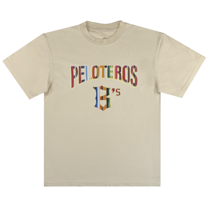 The Oakland Beisbol Tee by Oakland Ballers features "PELOTEROS" in bold, multicolored letters on a beige short-sleeve shirt, with a stylized “H’s” logo beneath—ideal for Pioneer League and Oakland Ballers fans.