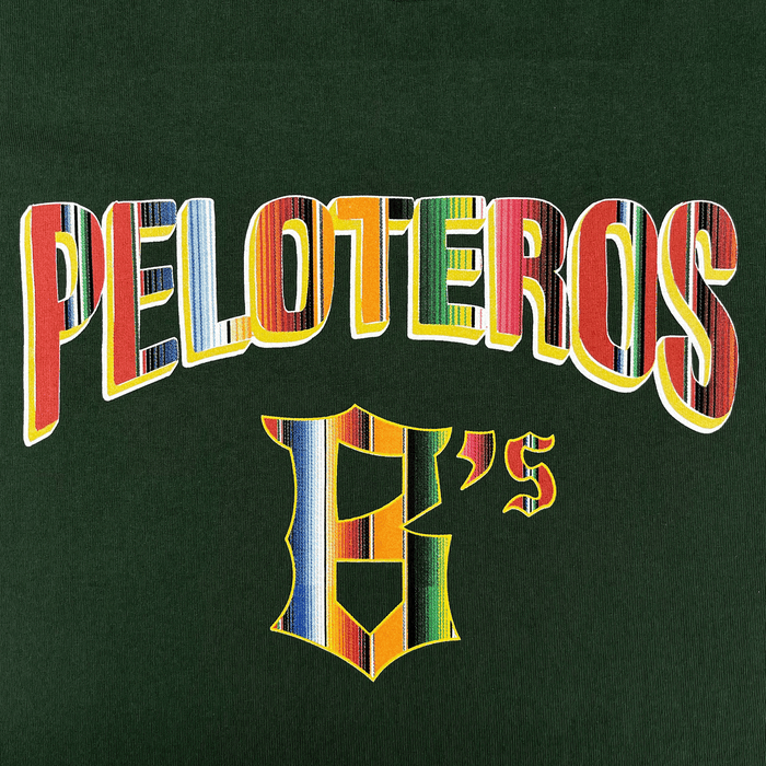 “PELOTEROS” appears in bold, multicolored letters above a matching stylized "E’s" on a dark green Oakland Beisbol Tee by the Oakland Ballers, with vibrant stripes inspired by traditional textiles.