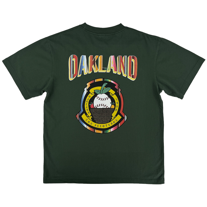 The Oakland Beisbol Tee by Oakland Ballers features a dark green design with bold “OAKLAND” in retro font on the back, plus a circular emblem below with a baseball, oak leaf, “LOS PELOTEROS,” and Pioneer League–inspired details.