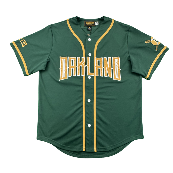 The Oakland Ballers’ Oakland Button Up Jersey is green with “OAKLAND” in bold yellow and white on the chest, yellow trim, white buttons, a crossed bats patch, and “ATHLETICS” in yellow—perfect for fans of this Oakland baseball team.