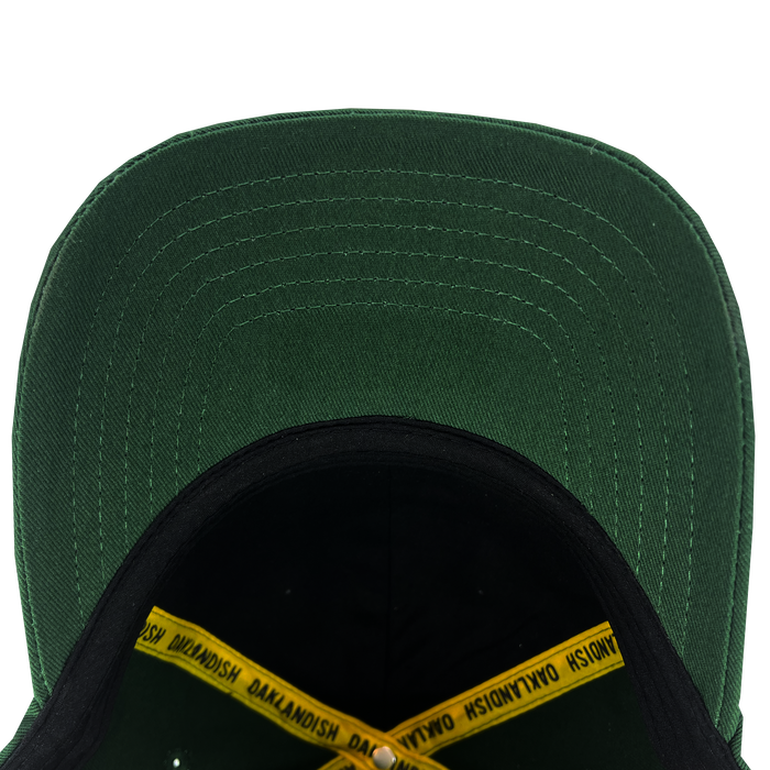 The Oakland Flag Dad Hat by Oaklandish, seen from above, reveals its interior and the underside of the bill. Inside, it highlights a black sweatband and a yellow hat band with "OAKLANDISH" printed repeatedly in black. The detailed stitching on the bill is visible, showcasing a series of parallel lines inspired by the design of the Oakland flag.