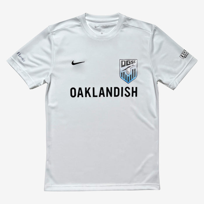 Product Description: The Oakland Genesis Home White soccer jersey features a white short sleeve design with striking black "OAKLANDISH" text across the chest. The left chest proudly displays the Nike logo, while the right chest showcases a DSC shield logo. On the left sleeve, “Flyer” is inscribed, and “SEE SUPPORT EXPAND” adorns the right sleeve, symbolizing support for the Oakland Genesis youth soccer nonprofit organization. Presented by Partner, this jersey combines style and community spirit.