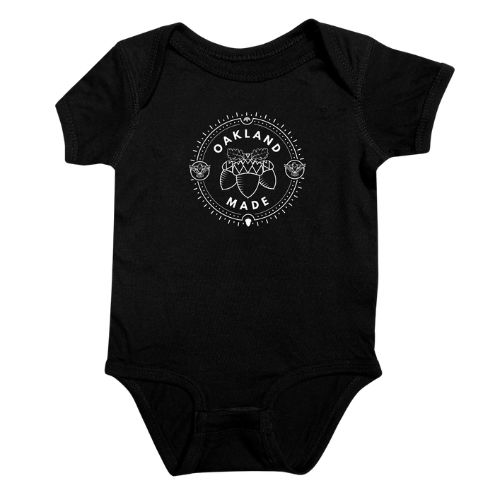 Black infant one-piece with a white circle graphic with the words “Oakland Made” and hand-drawn chestnuts.