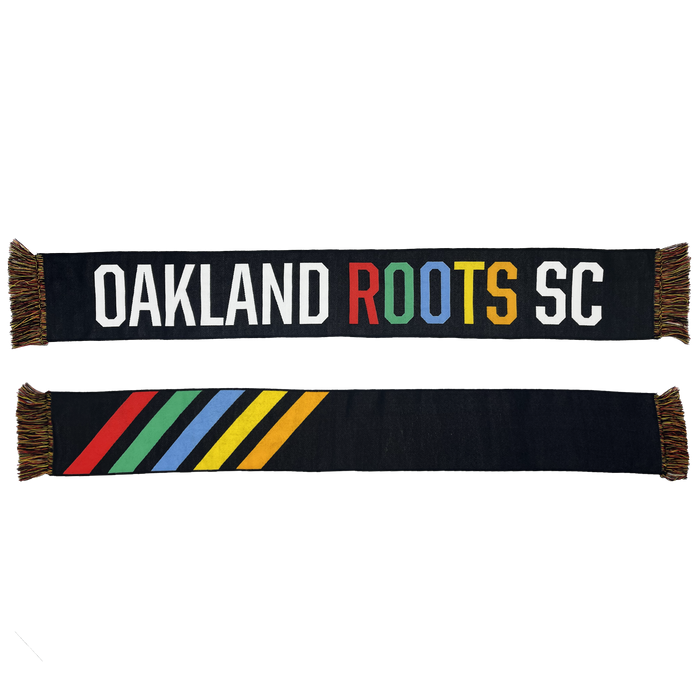 The Oakland Roots SC Alternative HD Woven Scarf is a vibrant accessory featuring colorful fringes on each end. One side showcases "OAKLAND ROOTS SC" in bold white letters, with "ROOTS" highlighted in rainbow colors. Representing the Oakland Roots Sports Club and its commitment to social good, the reverse side displays five diagonal stripes in red, blue, green, yellow, and white against a black background.