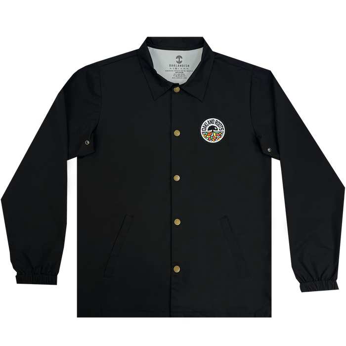 The Oakland Roots SC Coaches Jacket by Oakland Roots SC is showcased. This black, water-resistant premium jacket has gold snap buttons, a collar, elastic cuffs, and a logo patch on the left chest area. The circular logo reads "Grand Rhythm" surrounding a colorful design. The interior tag states "Grand Rhythm" and "Diamond Supply Co.