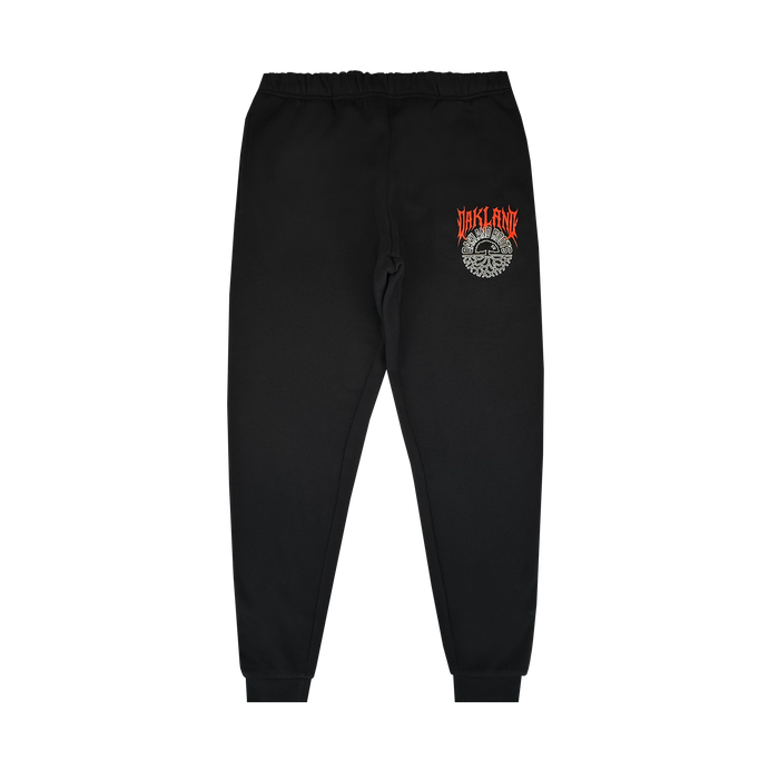 The Oakland Roots SC Forge Pant is a black men's sweatpant with elastic waistband and cuffs. Features red and orange "STAFF FIRE" text above a white graphic on the left thigh. Plain white background. From Oakland Roots SC.