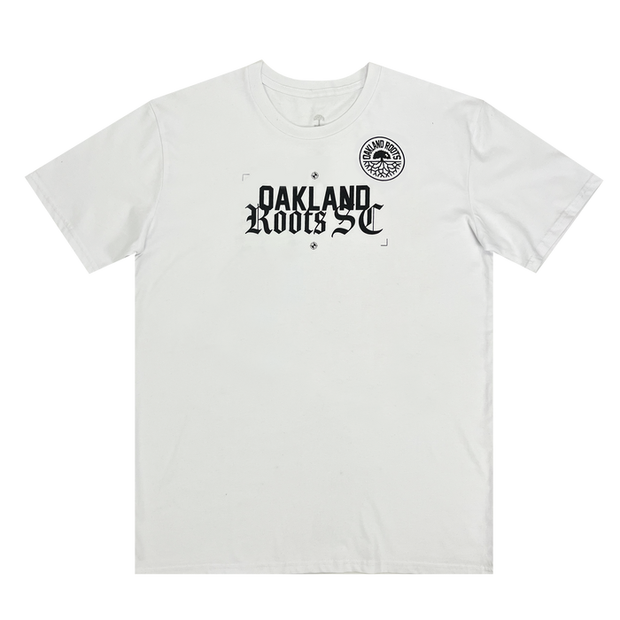 Introducing the Oakland Roots SC Futbol Town Tee by Other—this white short-sleeve t-shirt showcases a striking “OAKLAND Roots SC” print in bold black gothic font across the chest. A circular black and white Oakland Roots Sports Club logo is positioned above the text, near the left shoulder. The tee features a simple design with no additional graphics.