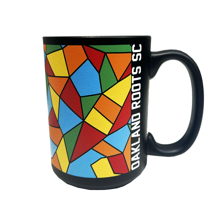 The Oakland Roots SC Mosaic Coffee Mug boasts a vibrant geometric pattern featuring an array of red, green, blue, yellow, and orange shapes on its black surface. Adorned with the text "OAKLAND ROOTS SC" vertically in white alongside the handle, this mug is perfect for soccer fans. The handle matches the sleek black design of this Oakland Roots Sports Club item.