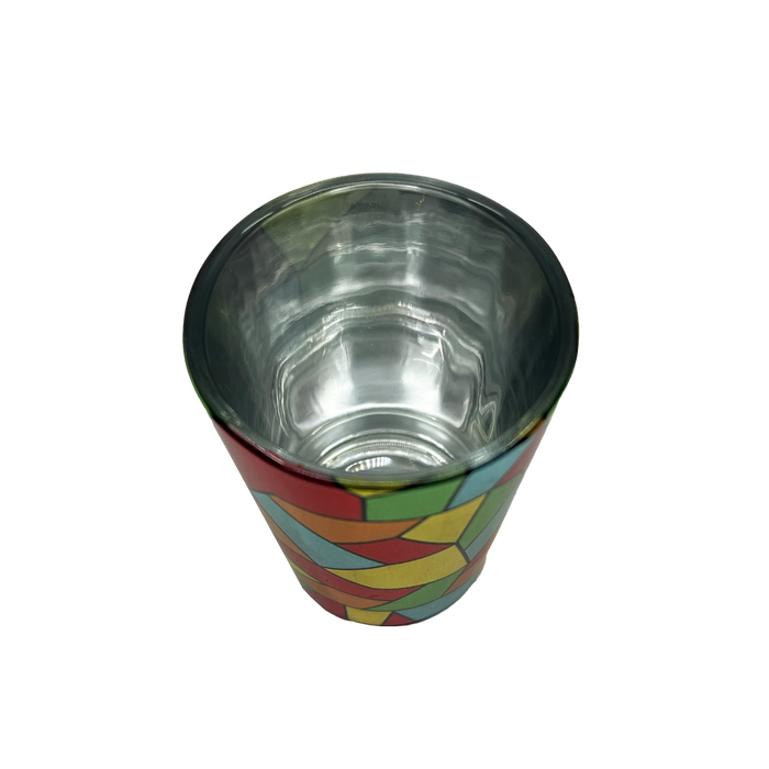 The Oakland Roots SC Mosaic Shot Glass by Oakland Roots SC is pictured. This small, metallic, cone-shaped shot glass boasts a colorful geometric pattern on its exterior, featuring red, yellow, green, and blue shapes. The interior is a reflective shiny silver. The empty cup is photographed against a plain white background.