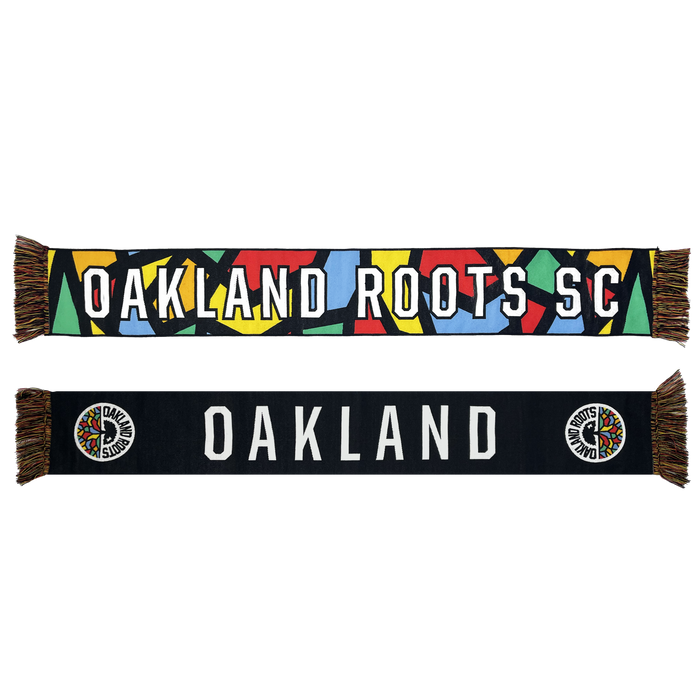 Two Oakland Roots SC OG HD Woven Scarves are shown. The top scarf features a colorful geometric pattern with "OAKLAND ROOTS SC" written in white letters. The bottom scarf is black with "OAKLAND" in large white letters and a colorful team logo at each end, with multicolored fringe on both scarves. Embrace the spirit of social good with every wear from this iconic sports club collection by Oakland Roots SC.