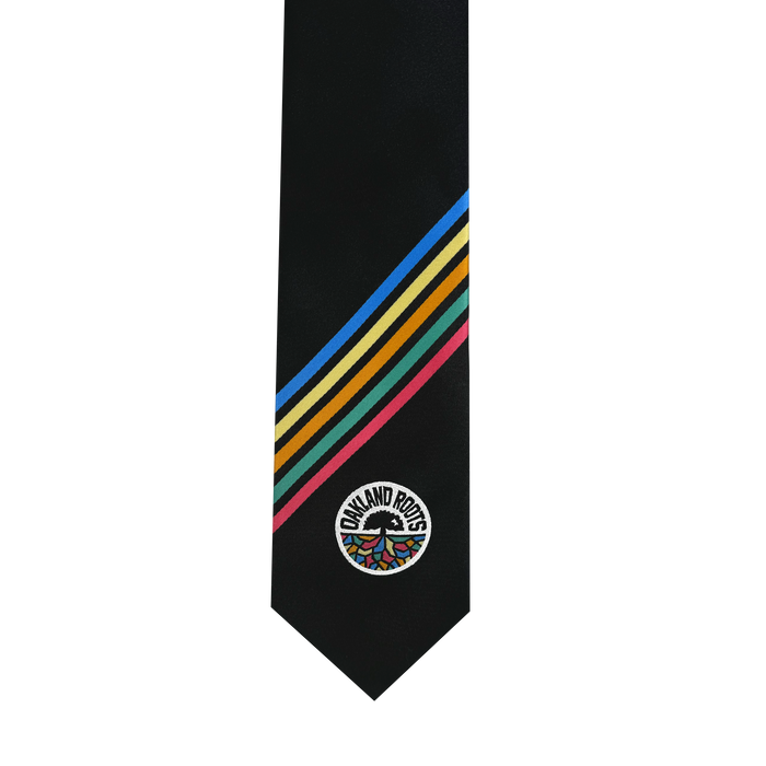 The Oakland Roots SC Tie, by Oakland Roots SC, features a black background with five diagonal stripes in yellow, blue, green, red, and pink adorning the left side. Near the bottom tip is an embroidered circular logo of the Oakland Roots that encircles a multicolored tree design, capturing the essence of Oaklandish style with a commitment to social good.