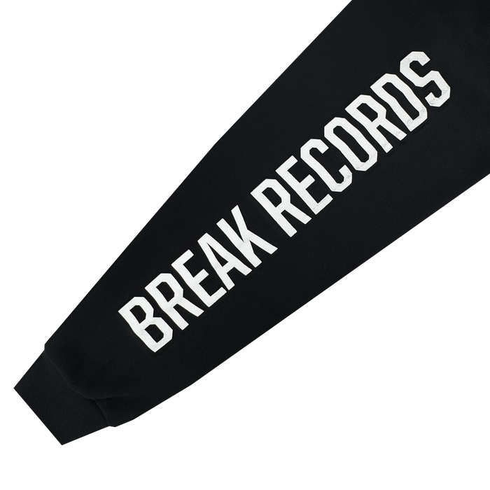 A black heavyweight Oakland Roots SC X Break Free Hoodie sleeve features bold white “BREAK RECORDS” text along its length, angled diagonally on a plain white background—showcasing this standout men’s pullover from Oakland Roots SC.
