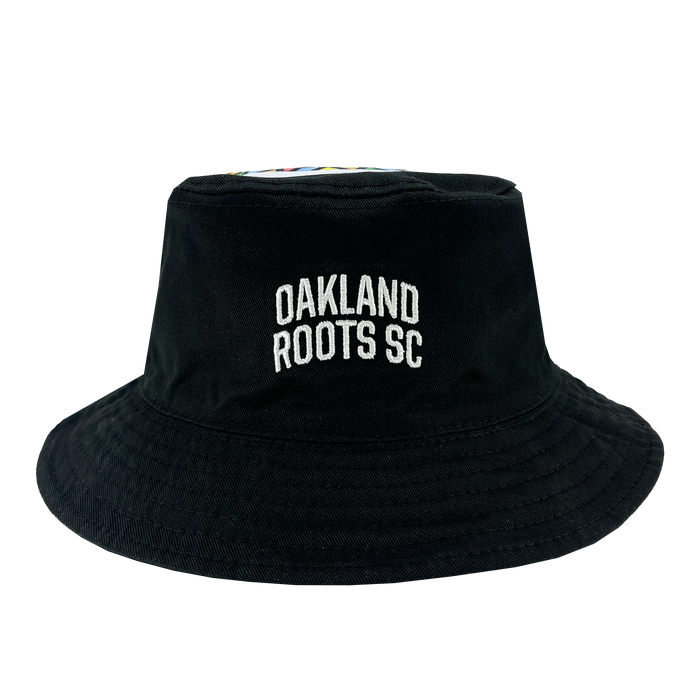 A black reversible bucket hat named the "Oakland Soul & Roots SC Reversible Bucket" by Oakland Roots SC, featuring "OAKLAND ROOTS SC" embroidered in white on the front. The hat has a classic brim and appears to be made of a fabric material, with a smooth, slightly structured crown. The background is white, highlighting the hat's details.