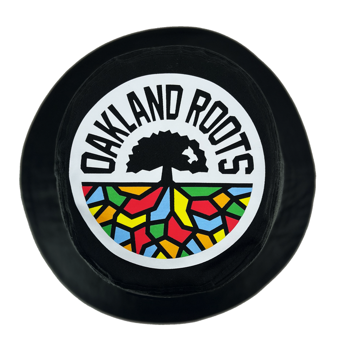 The Oakland Soul & Roots SC Reversible Bucket by Oakland Roots SC features a black circular patch with bold "OAKLAND ROOTS" text encircling a tree whose roots stretch into a vibrant mosaic pattern. The tree and text are rendered in black on a white background, while the mosaic is colored in red, yellow, green, and blue—making it the perfect accessory for your reversible bucket hat.