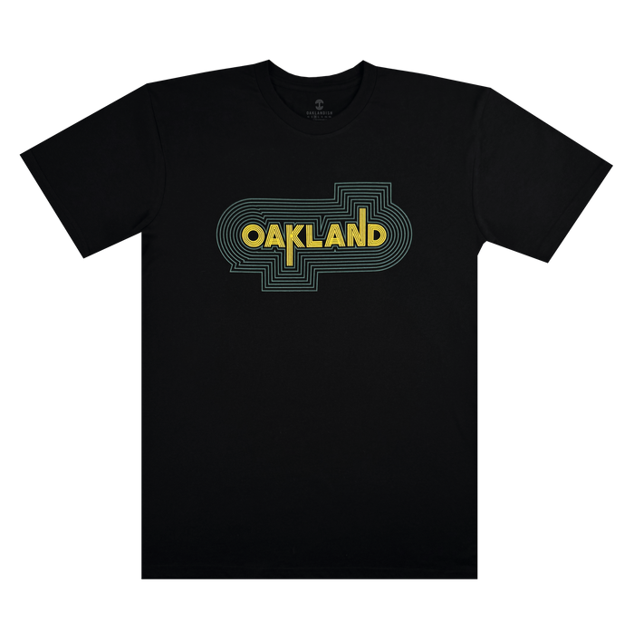 The Oaklandish "Oakland Sports Culture '68 Tee" is a black T-shirt with a yellow "Oakland" in stylized text reminiscent of the classic '68 sports era, framed by concentric blue-green lines forming a rounded rectangle on the chest.