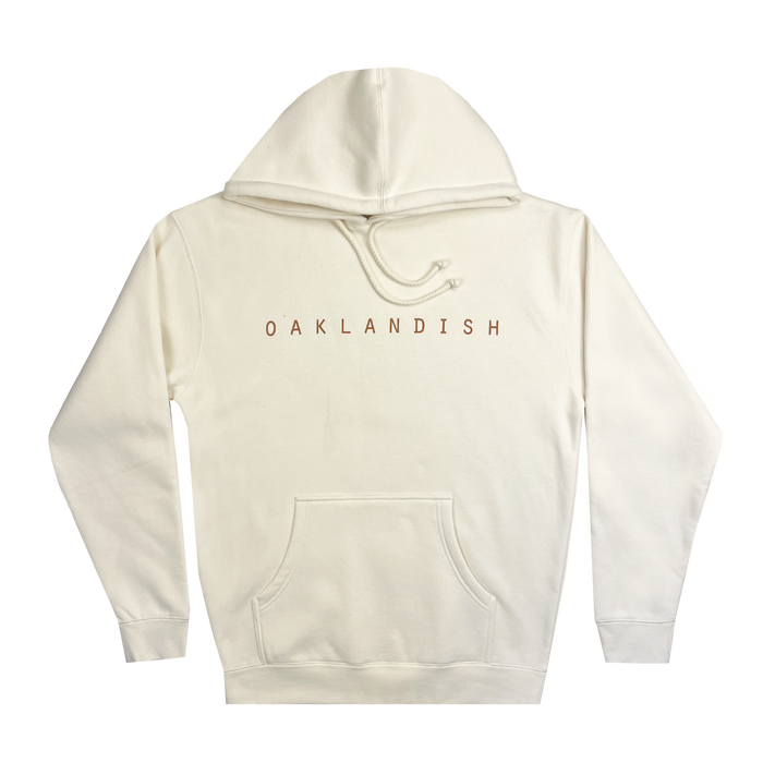 The Oaklandish Classic Hoodie, exhibited with its back facing the viewer, comes in a clean white and showcases "OAKLANDISH" in bold brown capital letters across the upper back. Designed for men, it features a front kangaroo pocket and an adjustable drawstring hood. The hoodie also includes ribbed sleeves and hem for a cozy fit, embodying the distinctive Oakland roots style.