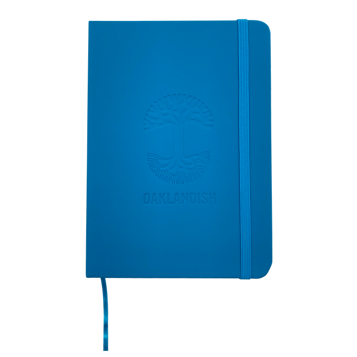 Top view of blue Oaklandish journal notebook elastic closure and bookmark with Oakalndish tree logo and wordmark embossed on the cover.