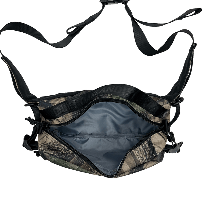 Top view of camo patterned cross-body bag with open zipper to reveal nylon lined insides.