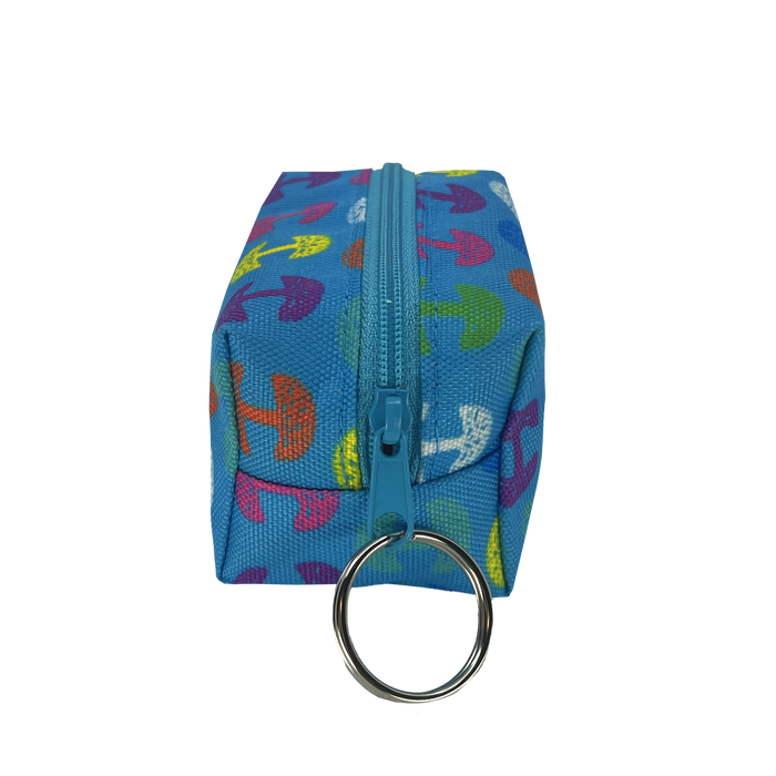 The Oaklandish Repeat Tree Mini Dopp by Oaklandish is a small, rectangular blue fabric pouch with a turquoise zipper running along the top. This mini keychain pouch features vibrant, multicolored umbrella patterns and has a silver keyring attached to one end of the zippered compartment.
