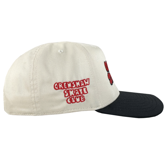 The Oaklandish Skate Club 2-Tone Hat, by Oaklandish, features a beige crown with a black brim. Red and white embroidery on the side highlights skate culture, while a red and black design accents the front. Shown against a plain white background.