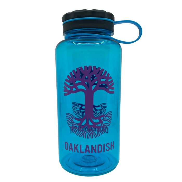 The Oaklandish Swig Bottle is a stylish blue reusable water bottle featuring a black screw cap and a blue loop handle. This BPA-free drinkware is adorned with a purple graphic of an intricately rooted tree and branches, accompanied by the word "OAKLANDISH" in matching purple text below the design, ensuring fashionable hydration on the go.