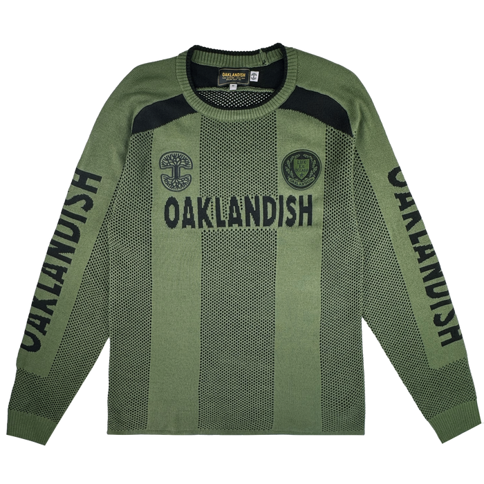 The Oaklandish Terrace Sweater is a men’s olive green knit with black “OAKLANDISH” text on the chest and sleeves, army-inspired black chest patches, ribbed collar/cuffs/hem, and a two-tone dotted pattern.