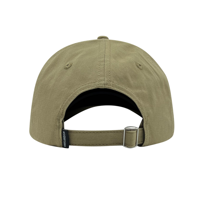 The image shows the back of the olive green Official Micro Logo Dad Hat from Oaklandish. It features an adjustable strap with a metal buckle and a small black tag with text next to the strap. The strap can be extended or shortened for a better fit, and the cap has two stitched eyelets on each side for ventilation.
