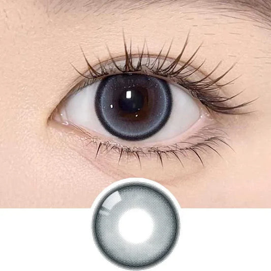 A close-up of a human eye with long lashes wearing Olola Meow Natural Siam Blue contacts by Olola, which enhance the iris. Below, a similar blue lens is shown separately on a white background.