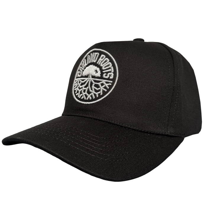 The ORSC 5 Panel Hat by Oakland Roots SC is a black cap with a curved brim, featuring a white tree patch and “Outland Roots” text. Inspired by Oakland Roots Sports Club, it's ideal for fans. Plain white background.