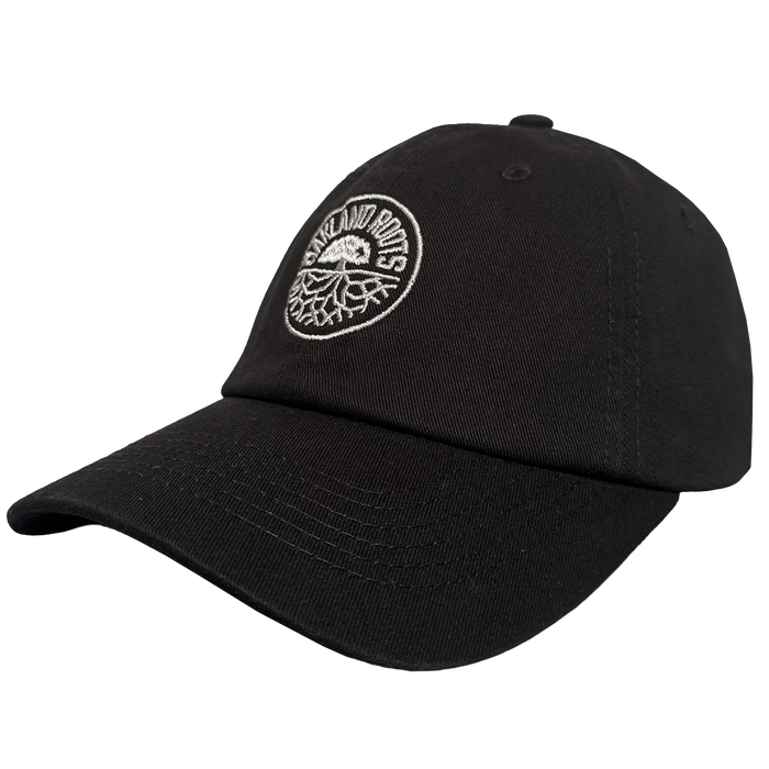 The ORSC Dad Hat by Oakland Roots SC is a black cap with a curved brim and an embroidered white circular "OAKLAND ROOTS" logo above a stylized tree, ideal for fans. Displayed on a plain, light background.