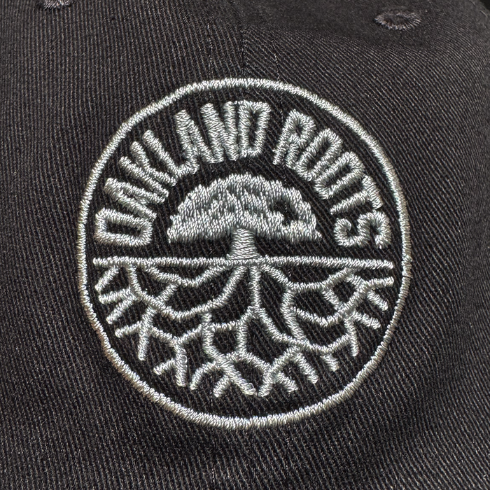 Close-up of a black ORSC Dad Hat by Oakland Roots SC, showcasing an embroidered circular tree and roots logo with "OAKLAND ROOTS" curved above in white—ideal for any Oakland Roots SC supporter.