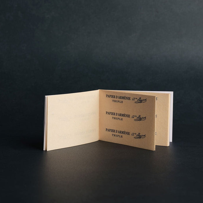 Open booklet of incense papers with text on a dark background
