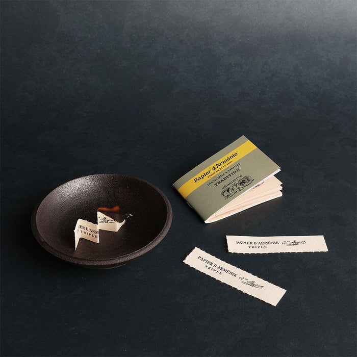 Incense papers and a small dish on a dark surface