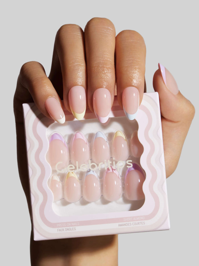 Hand holding a package of press-on nails with a neutral background