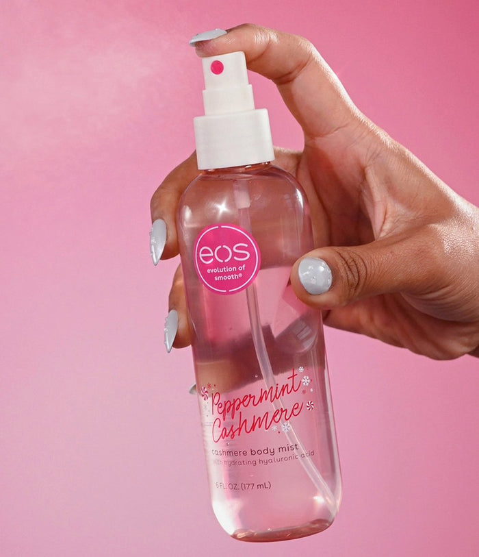 Hand holding eos Peppermint Cashmere body mist against a pink background