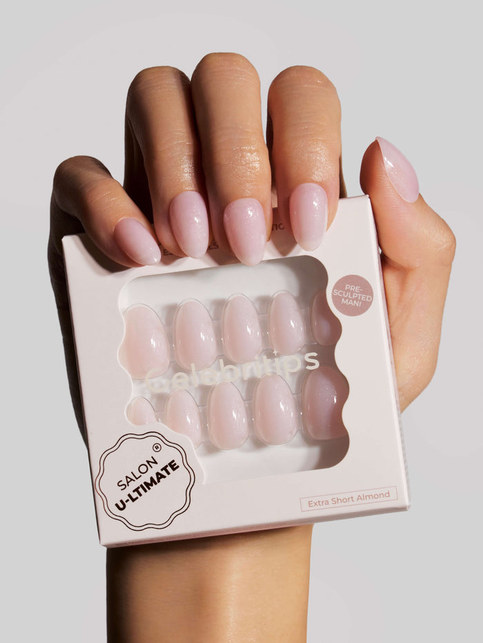 Hand holding a box of 'Salon Ultimate' pink press-on nails.