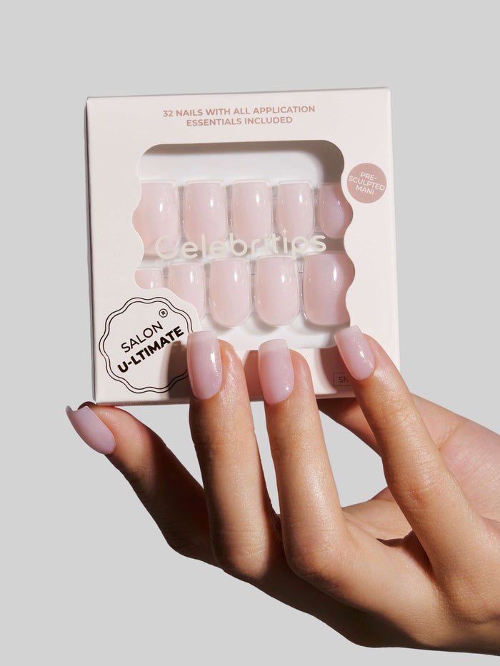 Hand with pink nails holding a package of press-on nails labeled 'Celebritips'.
