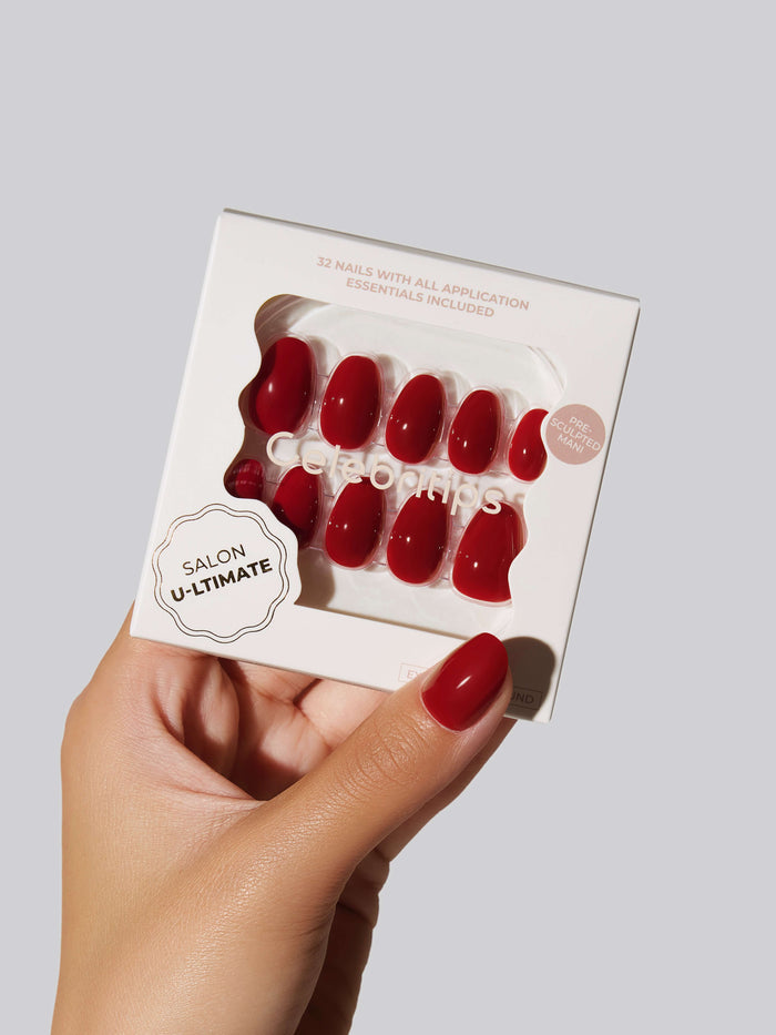 A hand holding a box of red Salon U-ltimate press-on nails.