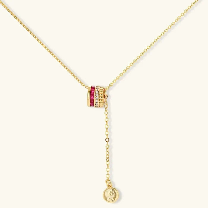 Royal Ruby Red Zirconia necklace with a gold cable chain, barrel pendant, red and clear stones, and dangling coin charm