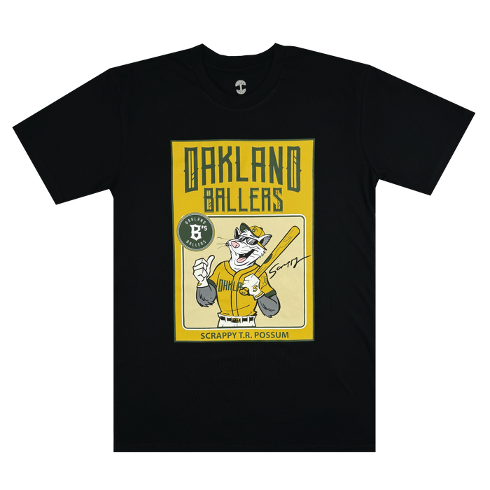 Introducing the "Scrappy Rookie Card Tee" by Oakland Ballers: This black T-shirt showcases a graphic of an illustrated possum dressed as a baseball player, holding a bat and proudly wearing an Oakland Ballers jersey from the Pioneer League. The text "Scrappy T.R. Possum" is featured below the image on a yellow background, along with an emblem displaying "Ballers Performance Apparel.