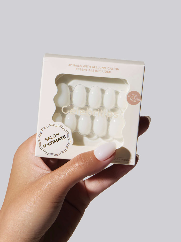 Hand with white nails holding a box of the same Celebritips press-on nails.