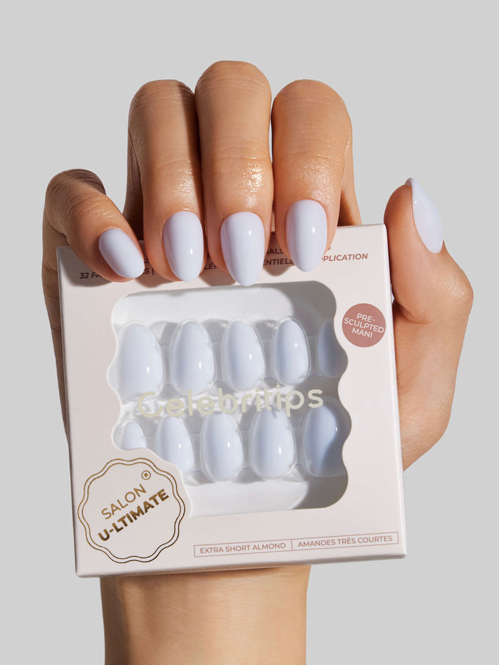 Hand holding a box of press-on nails with a neutral background