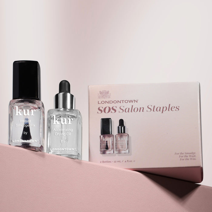 Two LONDONTOWN kur nail bottles and the S.O.S. Salon Staples box sit on a pink surface with soft shadows—your secret to a flawless, salon-quality manicure at home.